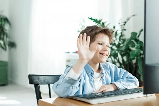 Boy_20Waving_20at_20Computer Smiling boy waving at the computer screen, participating in a virtual learning session