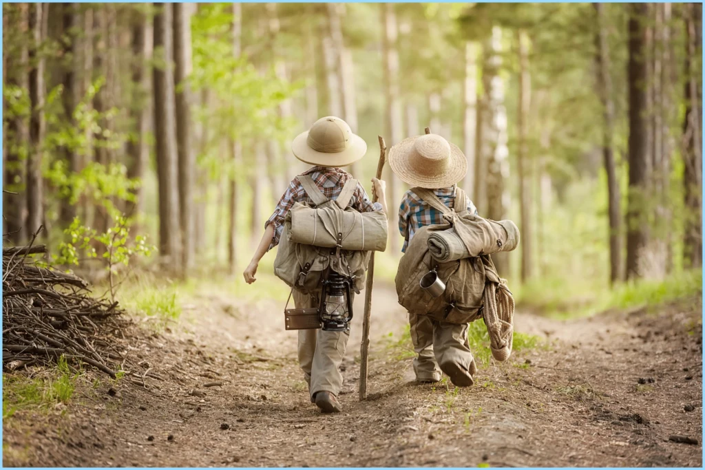 adventure forward Two children walking in nature with backpacks and hats